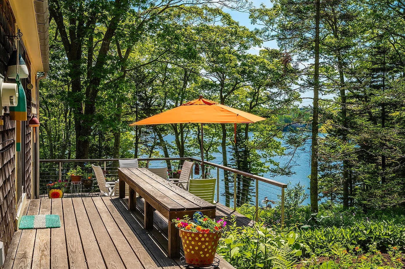 Deck dining table with orange umbrella overlooking Collins Cove